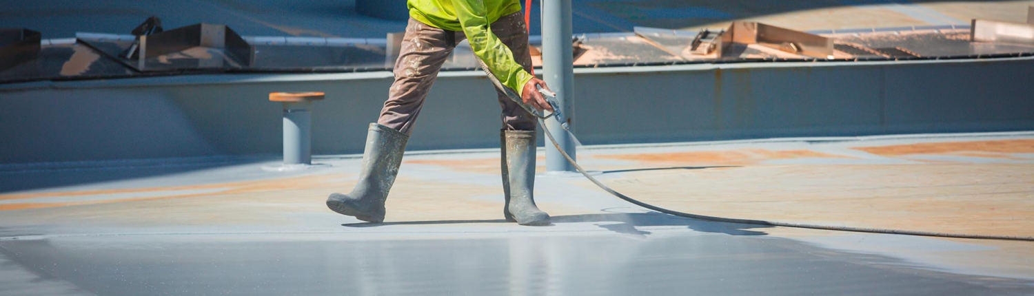Worker Spraying Coat On Flat Commercial Roof