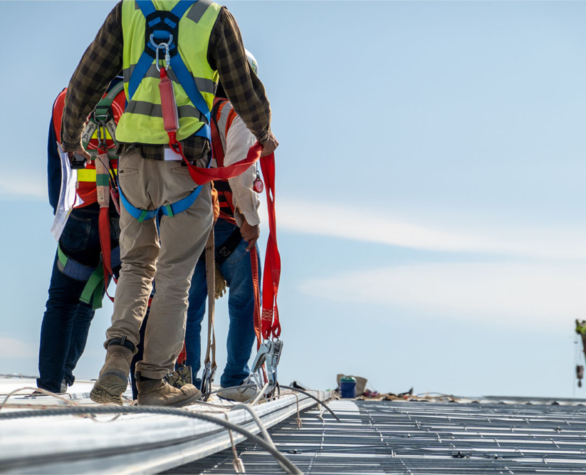 Workers In Harnesses Working On Metal Roof