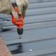 Workers Installing The Metal Sheet Roof By Electrical Drilling Machine