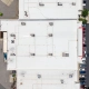 Aerial drone view of a large white commercial flat roof with multiple HVAC units, visible seam lines, and surrounding parking lot